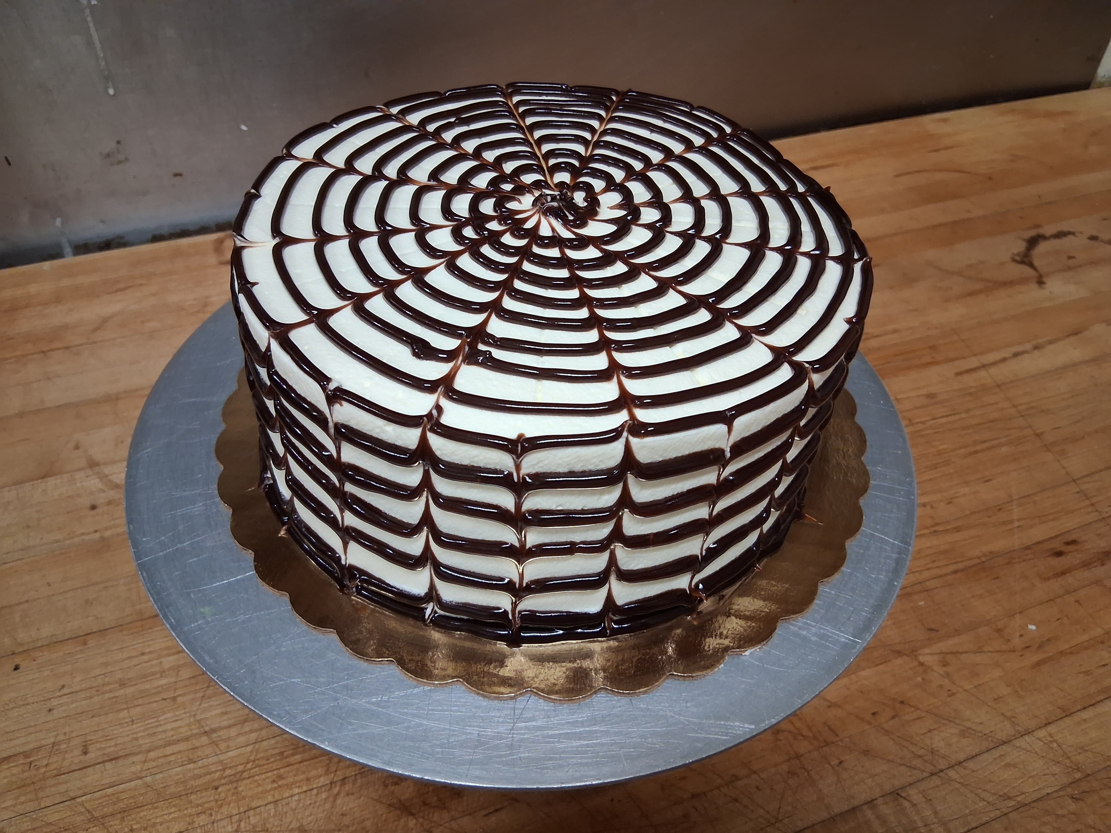 Cake with white frosting and chocolate web pattern decoration